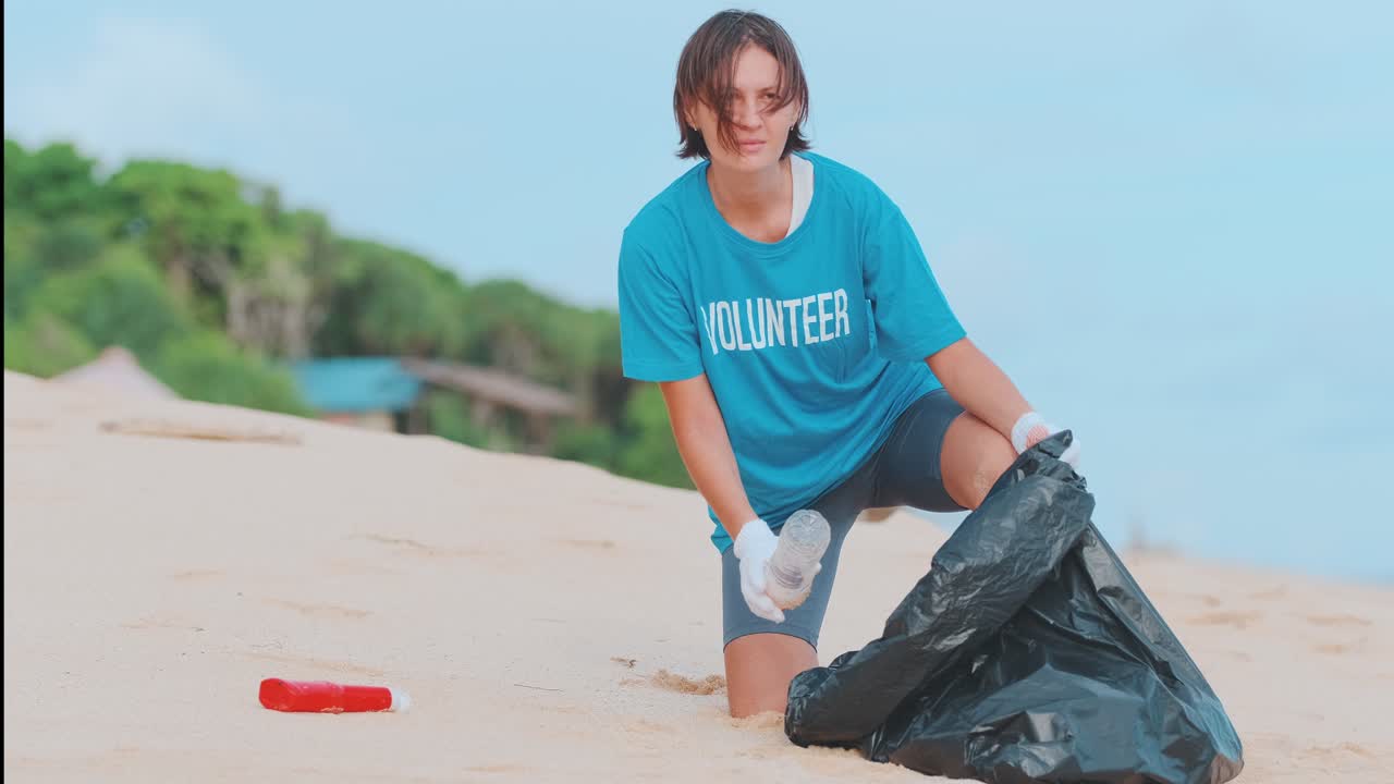 Young caucasian woman fights ocean pollution throws plastic bottles into bag