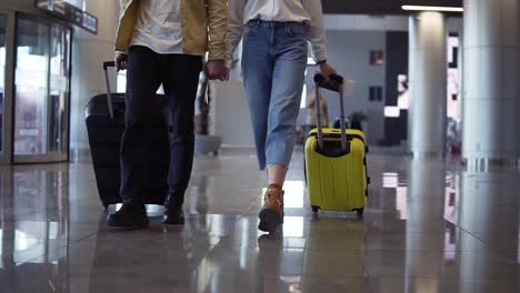 Cropped-Front-Footage-Of-Couple-Travelers-Are-Carrying-Their-Luggage-And-Holding-Hands