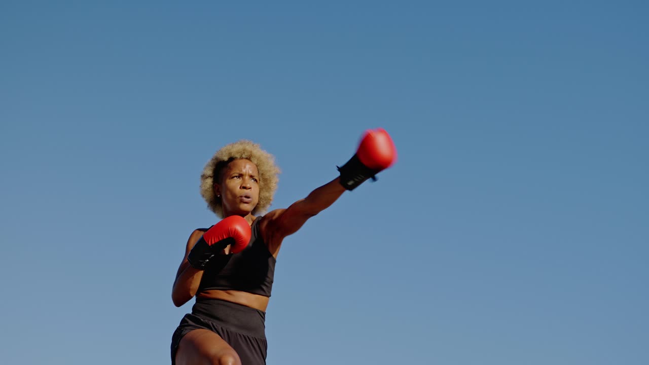 A woman is boxing wearing red gloves