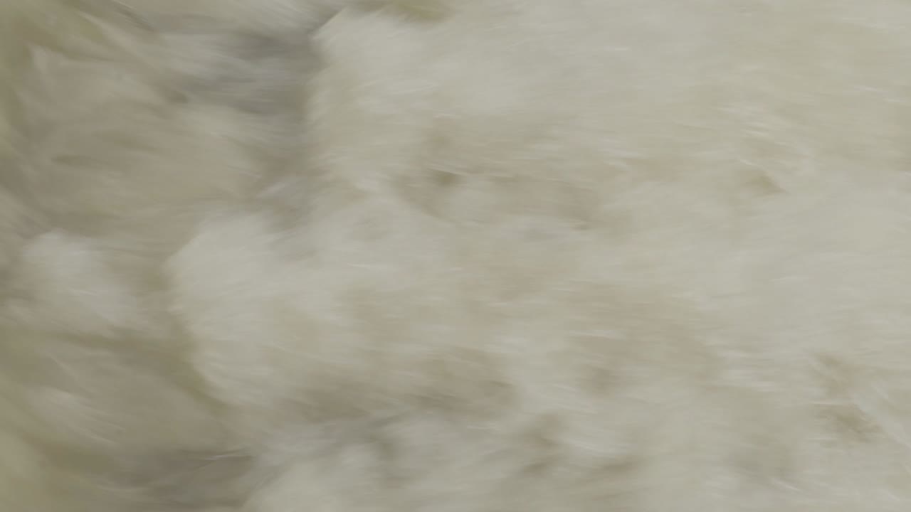 작은 폭포에서 많은 얼룩이 있는 더러운 갈색 물이 끓는 풀 프레임 클로즈업 샷