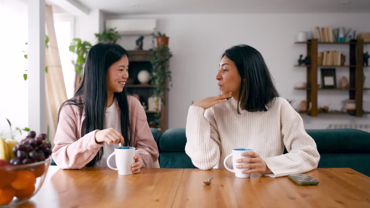 自宅でコーヒーを飲みながら会話する楽しそうな若い女性たち