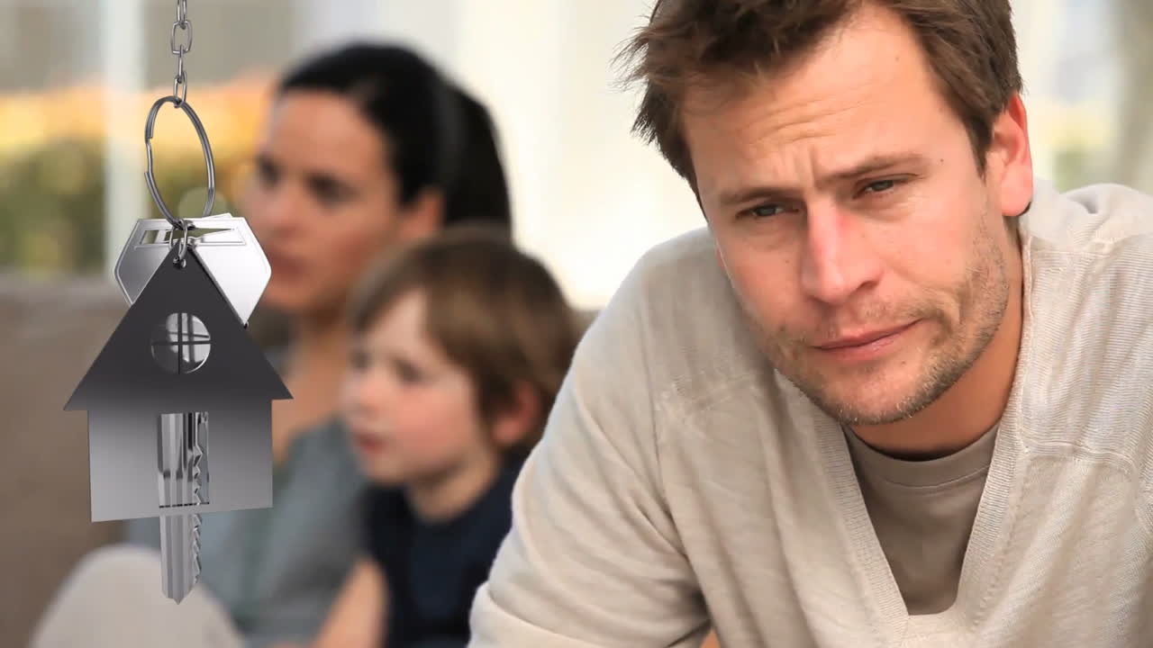 House keys and key fob hanging with worried man in the background