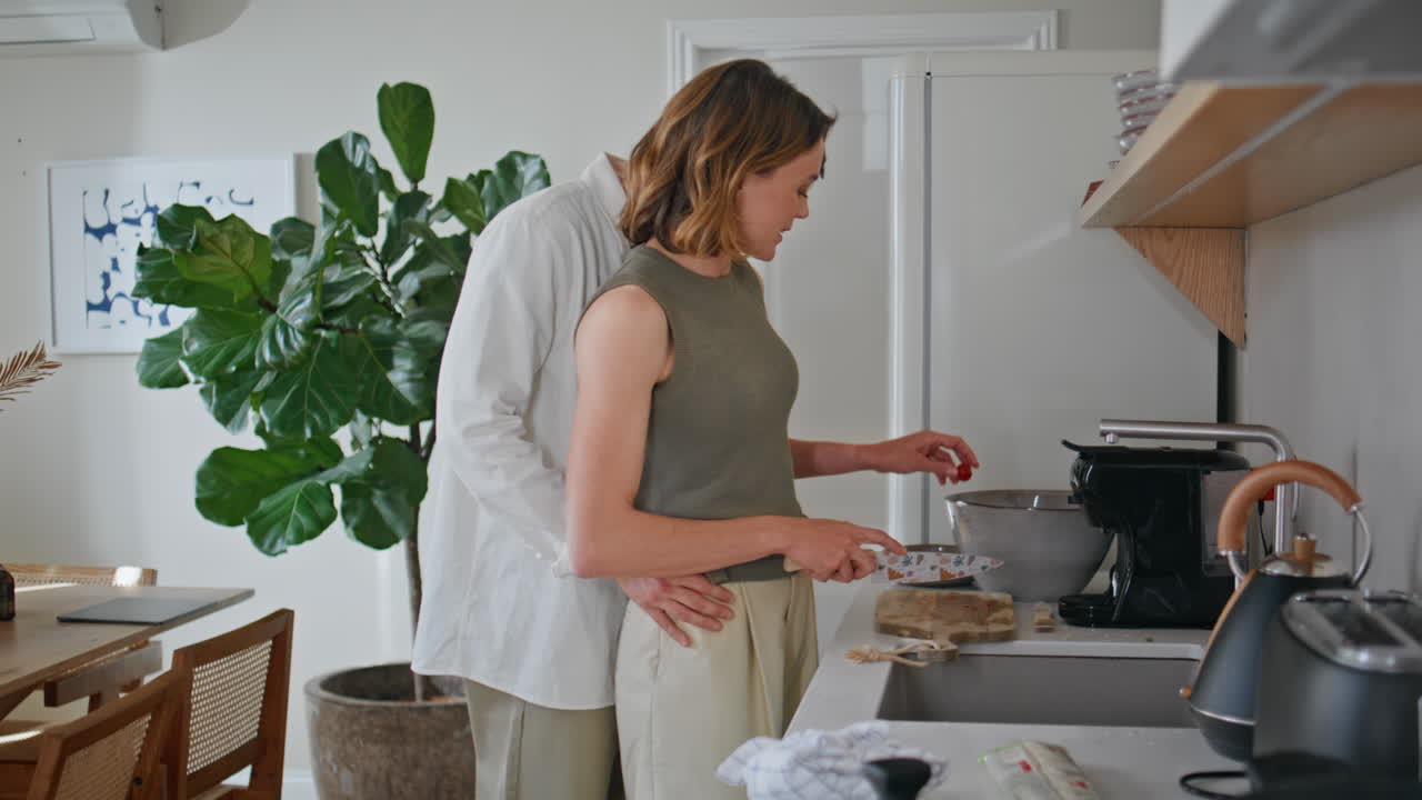 Primo piano di una coppia di coniugi che prepara la colazione a casa. Coppia che si abbraccia in cucina