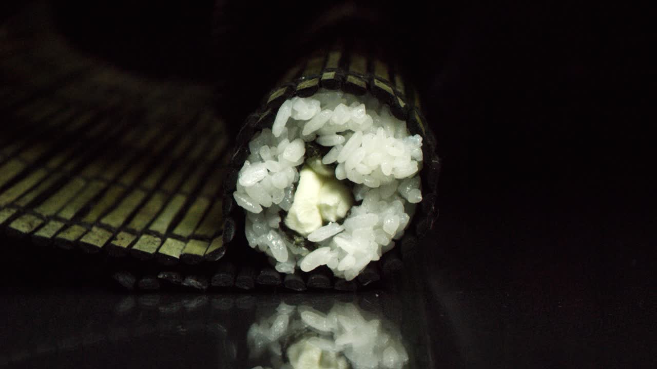 primer plano de un rollo de sushi en una alfombra de bambú