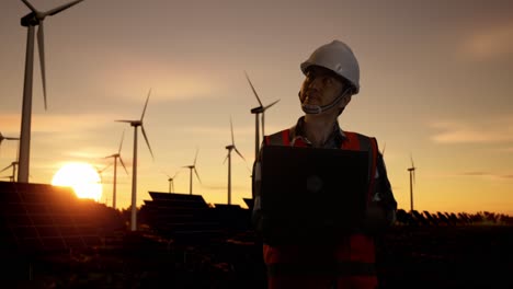 engineer at a wind and solar farm at sunset