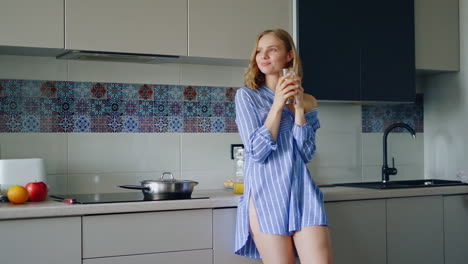 young woman in sleepwear drinking orange juice from glass