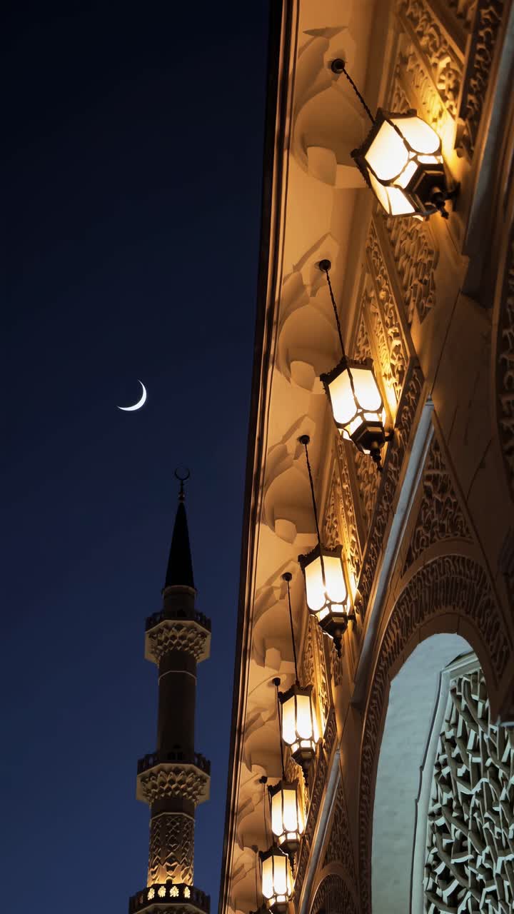 Un'inquadratura dal basso cattura un'architettura ornata e una luna crescente al crepuscolo, creando un'atmosfera serena.