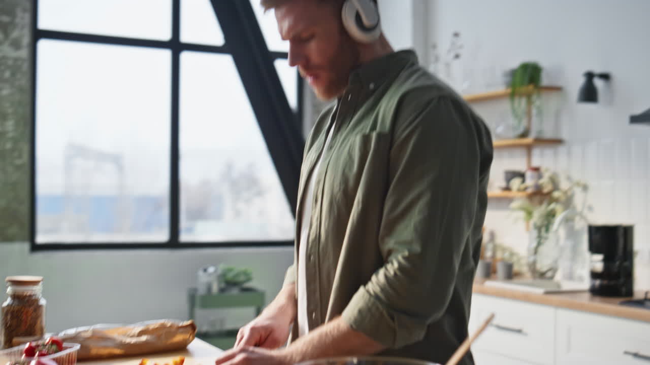 Guy hands slicing ingredients at kitchen listening music in headphones closeup