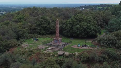 Aerial-view-sandstone-obelisk-war-memorial-Frodsham-hill-overlooking-Cheshire-Liverpool-skyline-left-orbit-shot