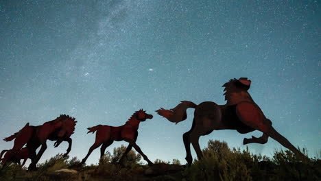 silhouetted metal horse sculptures beneath a stunning perseids meteor shower, with countless stars lighting up the desert night sky in a breathtaking celestial display. night time lapse