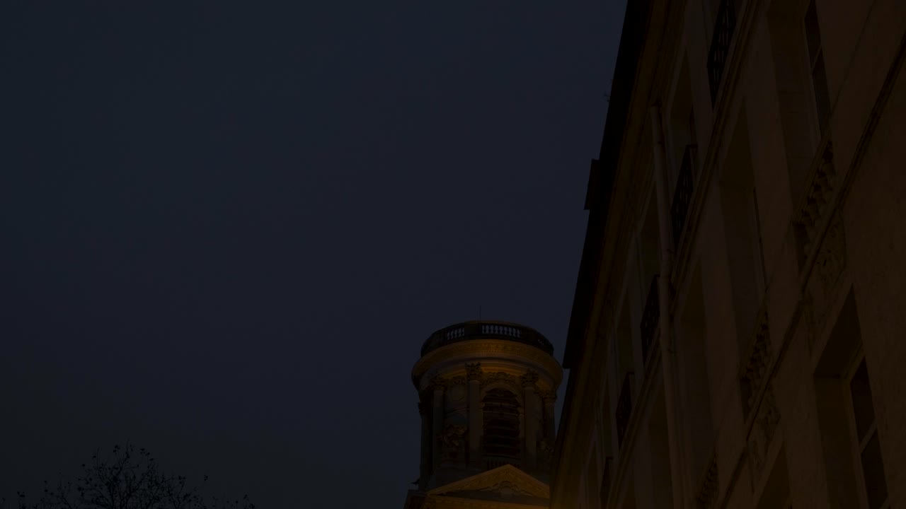 Low-angle shot of one tower of Saint-Sulpice Church glowing at night