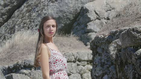 woman in a floral dress posing by ancient stones