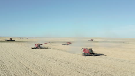 grandes máquinas de cortinas de barra de corte de agricultura industrial que cosechan grano de trigo en tierras de cultivo planas y expansivas en el campo actual rápido, saskatchewan, canadá