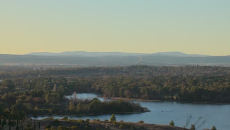 elevated view of canberra at sunrise with the parliament house spire and tree-covered suburbs stretching toward the horizon