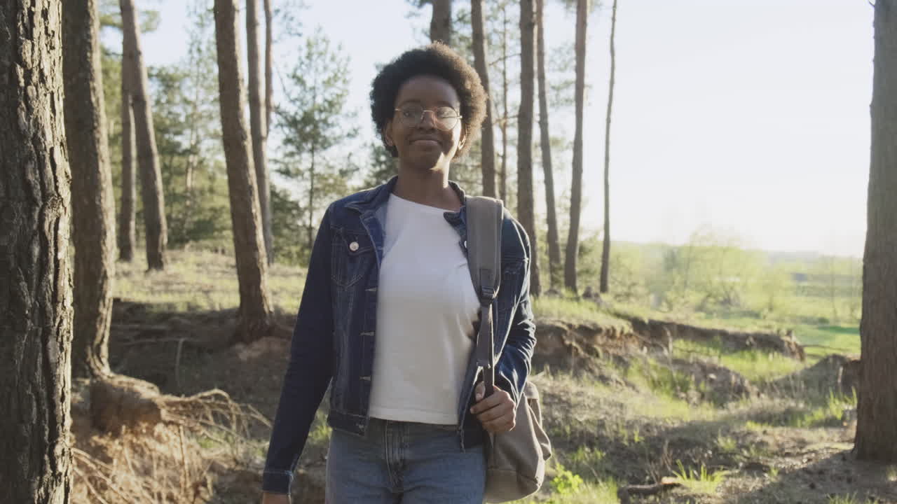 Una joven hermosa pasea por el bosque al atardecer.