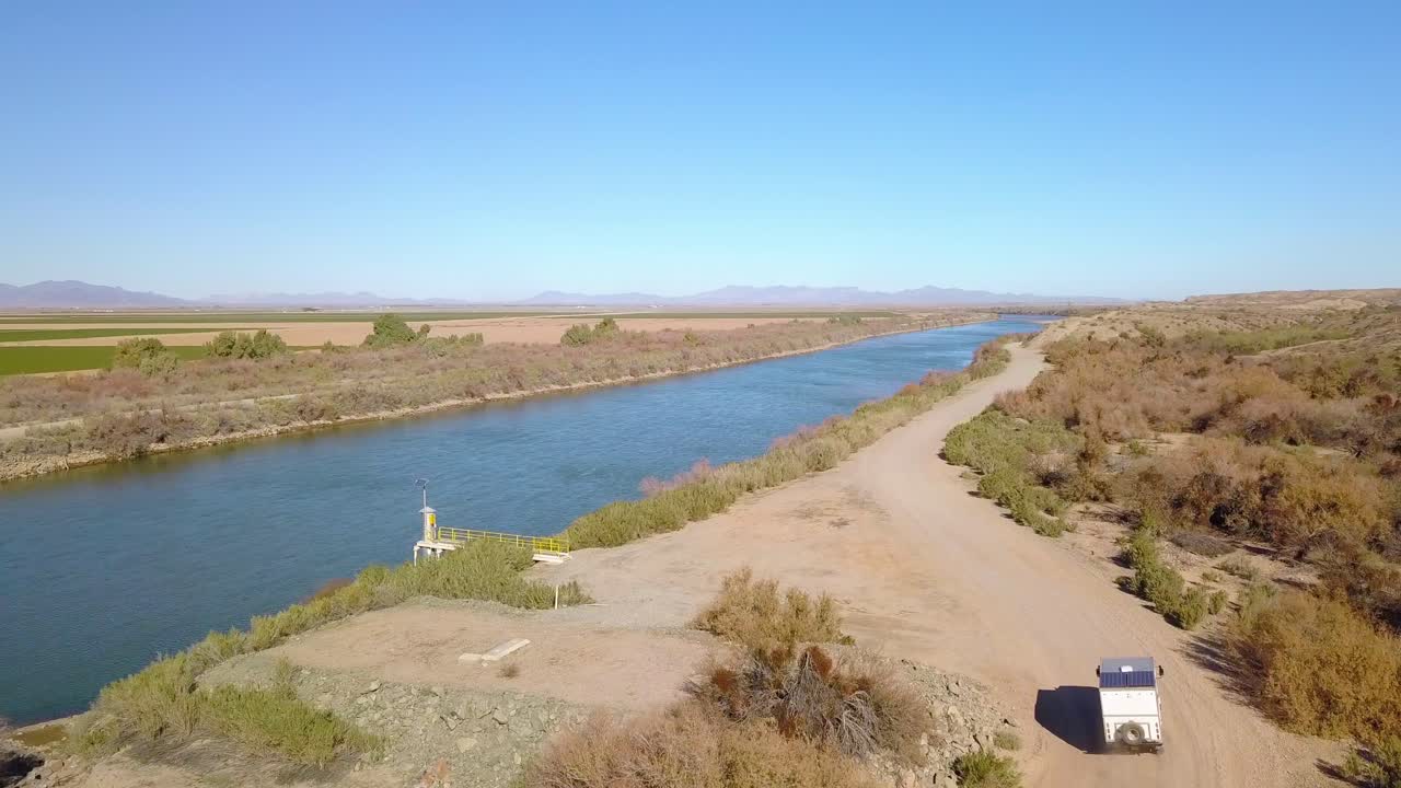 Aerial, drone shot following a RV van on a sand road, at Colorado river, sunny day, in California, USA