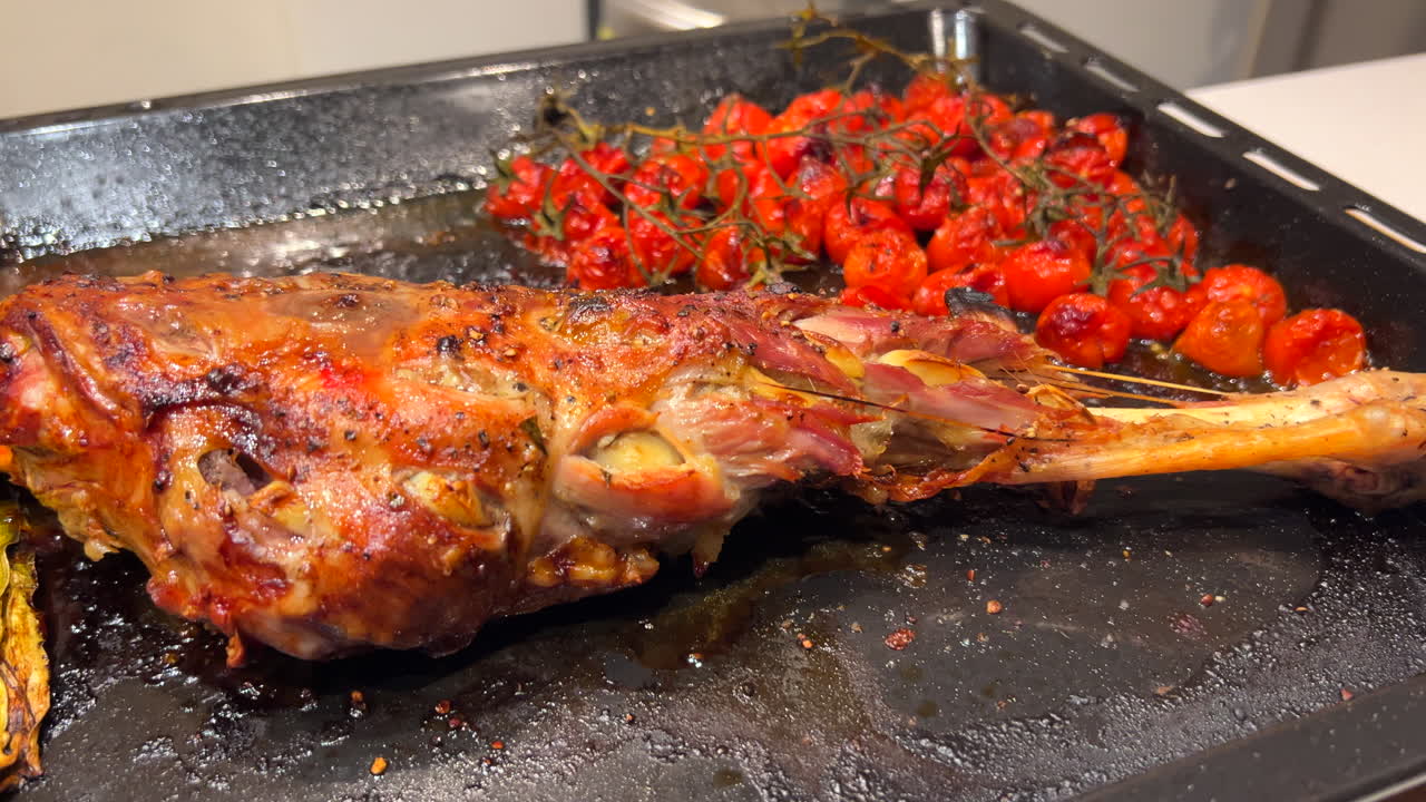 Tasty roasted leg of lamb with cherry tomatoes and potatoes, soft tender meat cooked in the oven, homemade dinner, 4K shot