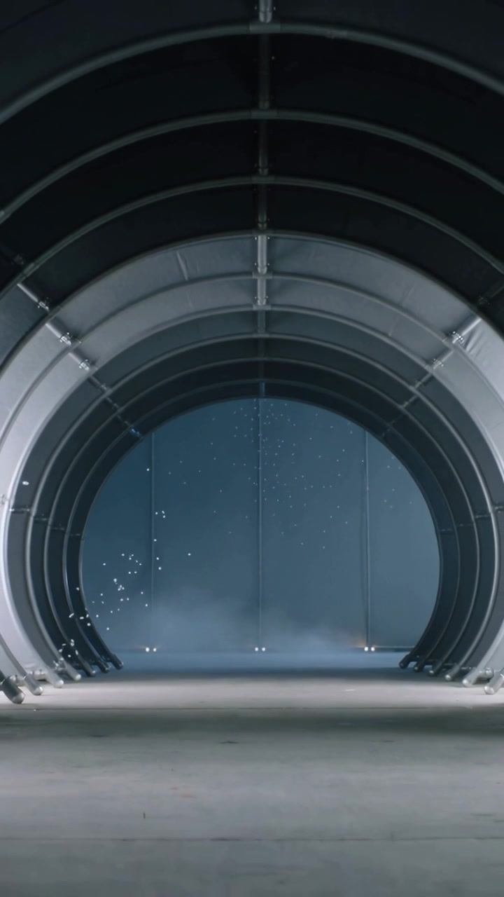 Video verticale: Telecamera che avanza, arco che rivela nervature imbullonate in un hangar, nebbia, scintille, mostrando dettagli.