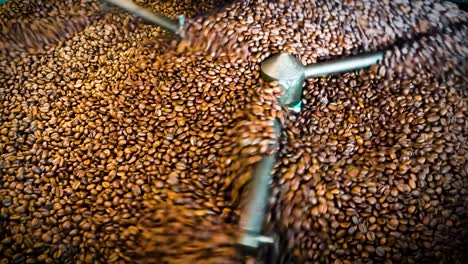 granos de café oscuro recién tostados mezclados y rotados por una máquina profesional con detalles de cierre
