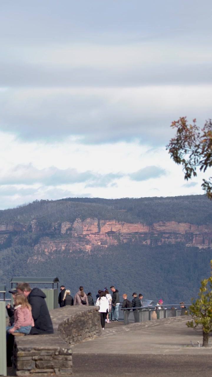 Turisti camminano lungo un belvedere pavimentato con vista su scogliere di arenaria a Katoomba, Australia