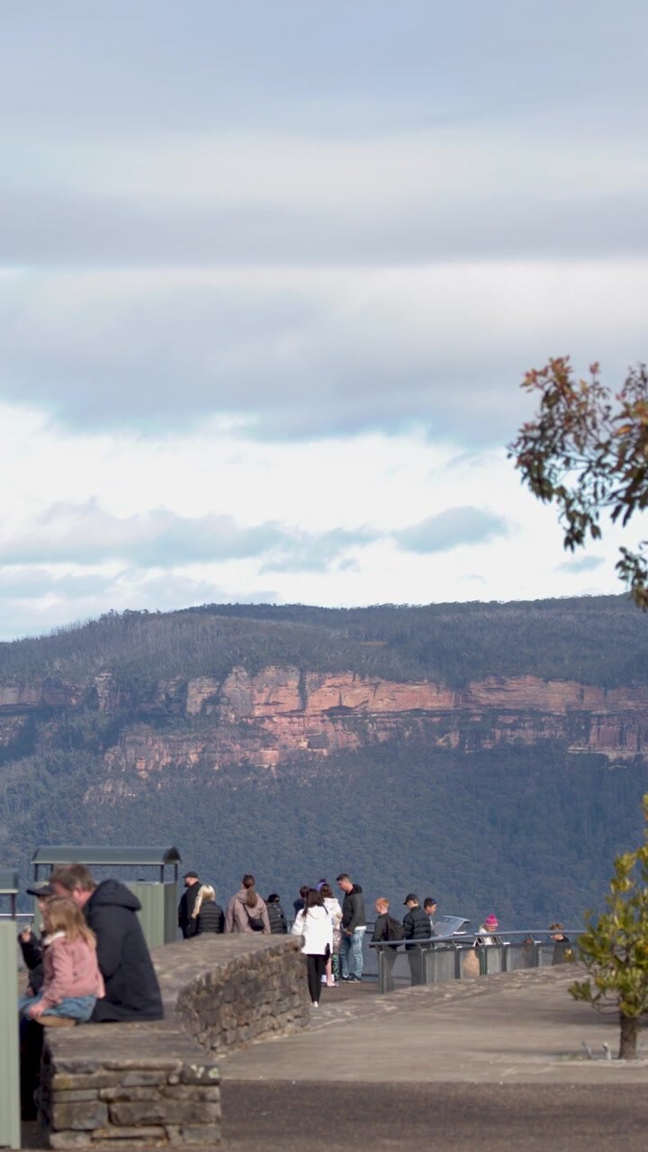 Turisti camminano lungo un belvedere pavimentato con vista su scogliere di arenaria a Katoomba, Australia