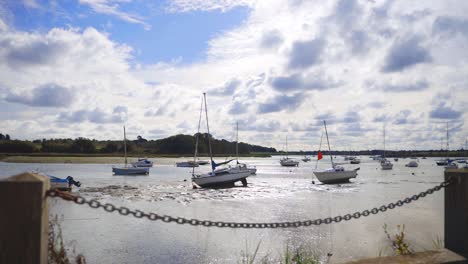 wide shot of boats in river at low tide in the mud