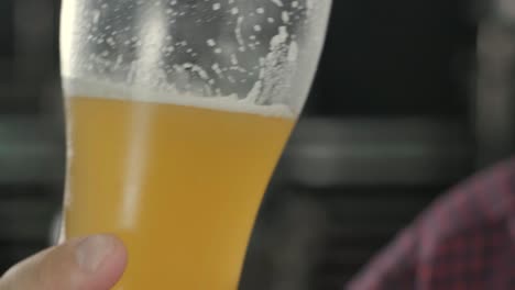un joven cervecero con un delantal de cuero está probando cerveza en una cervecería moderna
