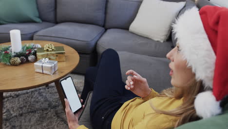 happy biracial woman wearing santa hat using smartphone at christmas, copy space, slow motion