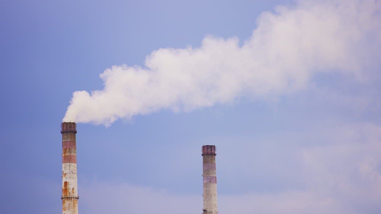 Industrial zone pipes making white thick smoke. Pipes of a plant polluting the environment. Low angle view.