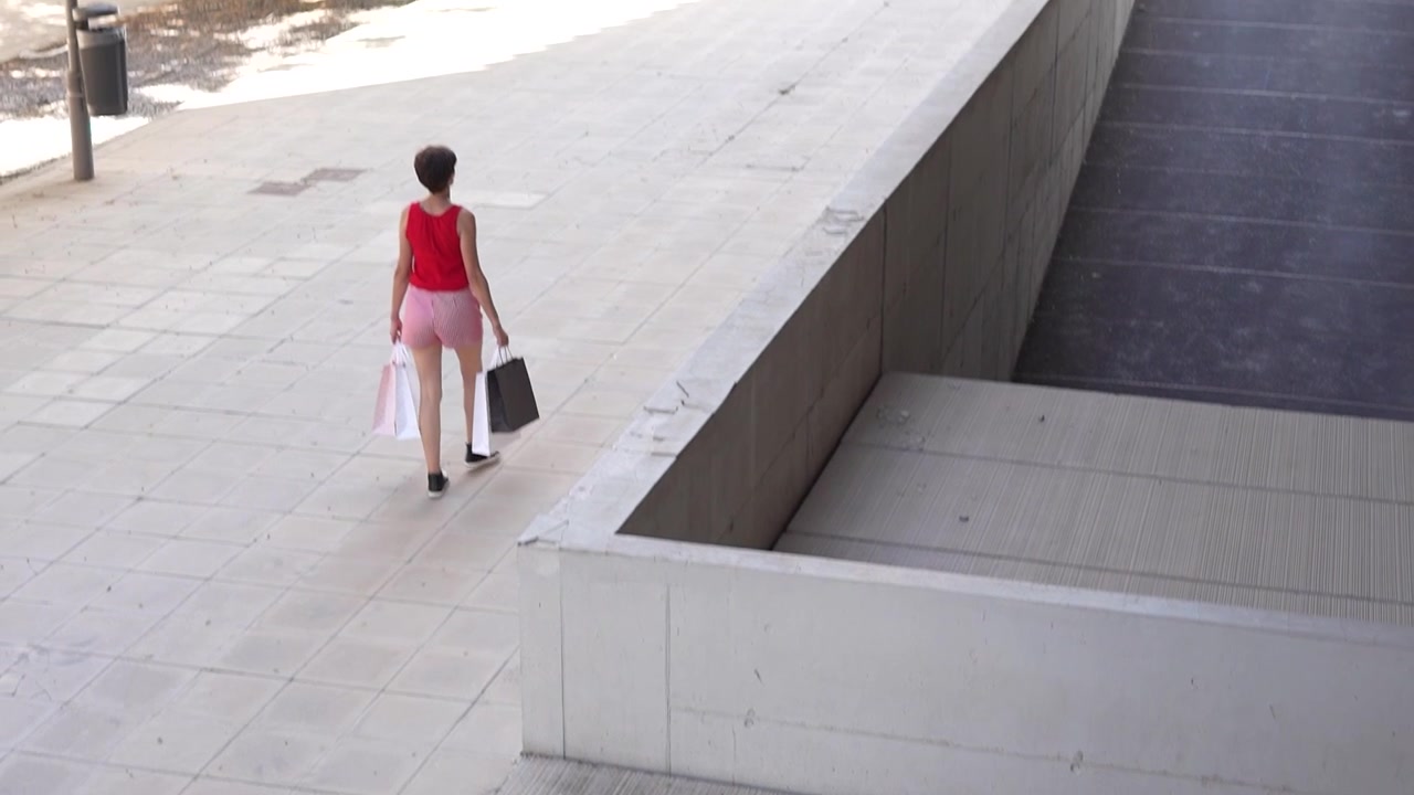 A carefree shopper carrying bags while walking on a vibrant city street during the day