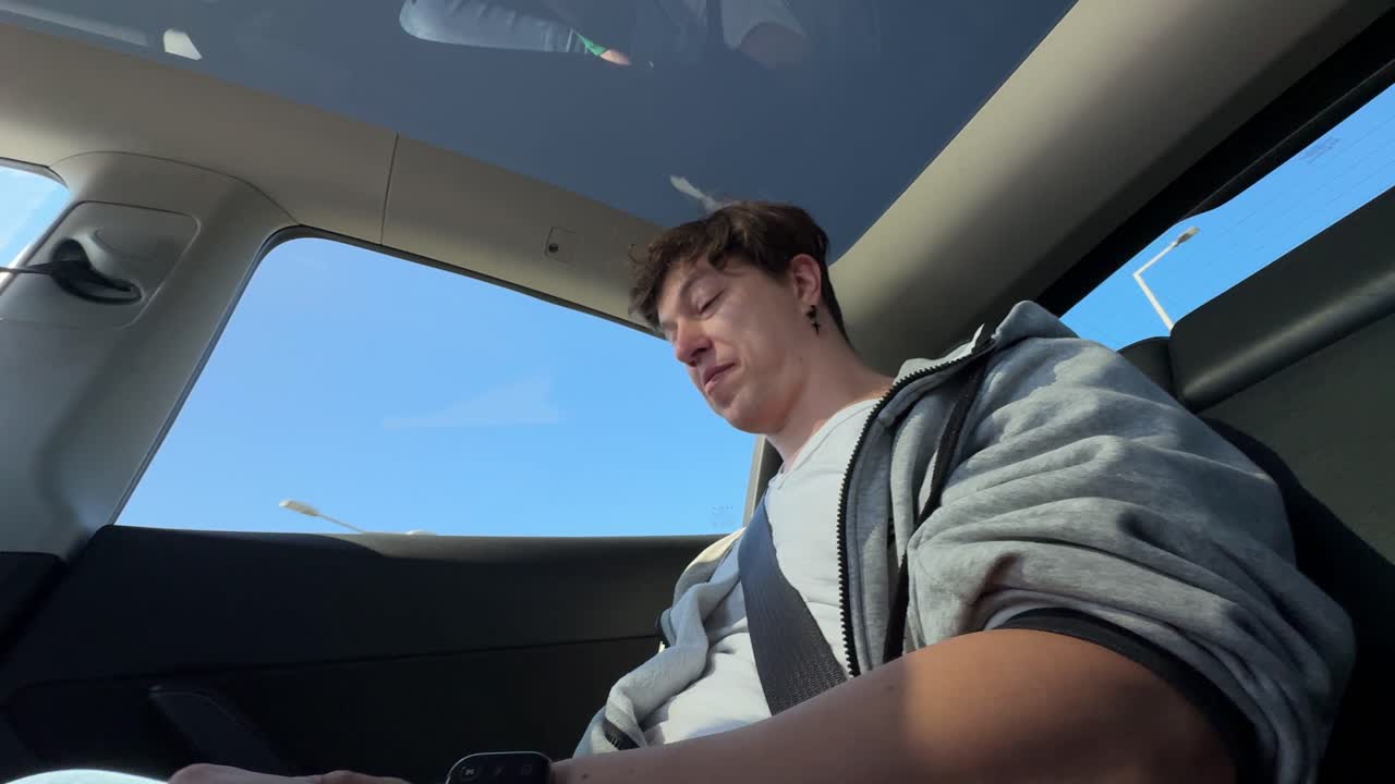 Man in backseat of a Tesla, looking out the window.