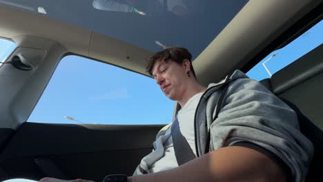 man in backseat of a tesla, looking out the window.
