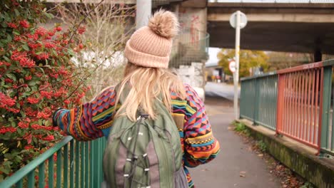 woman-touching-some-berry-bush-as-she-walks-by-it-and-smiles-into-the-camera-afterwards