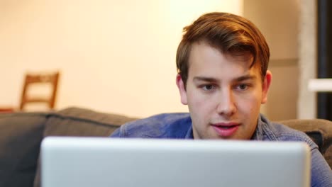 hombre sentado en el sofá y usando computadora portátil en la sala de estar