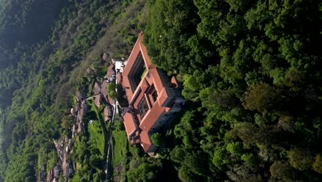 Aerial-orbit-around-monastery-in-mountain-forest-of-ourense-spain,-VERTICAL