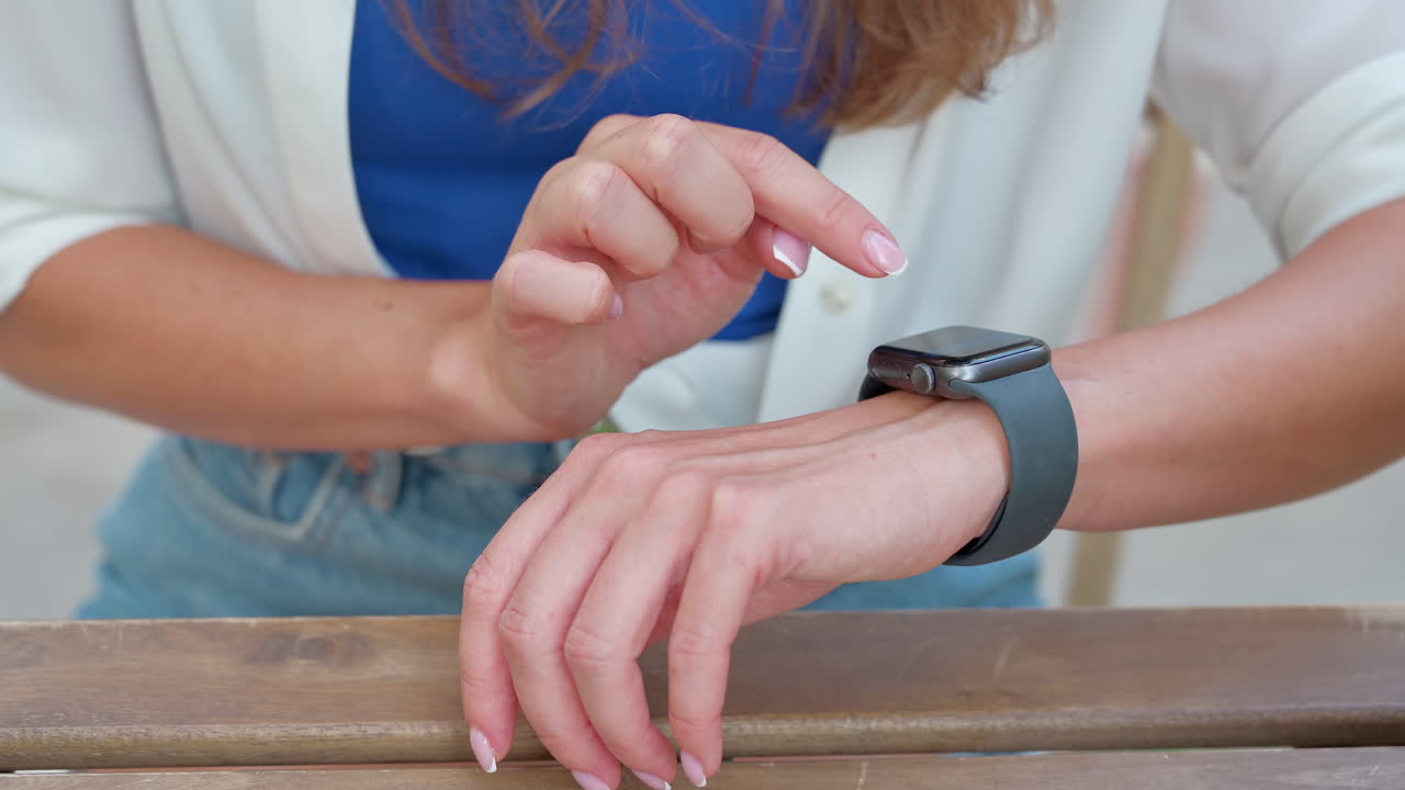 Primo piano di una donna che usa uno smartwatch su una terrazza