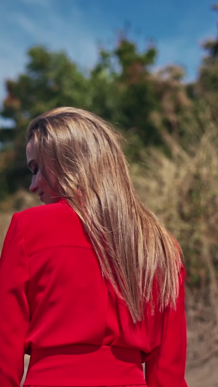 Sexy woman with long hair outdors. Backside view of a pretty woman in bright dress walking in nature. Slow motion. Vertical video