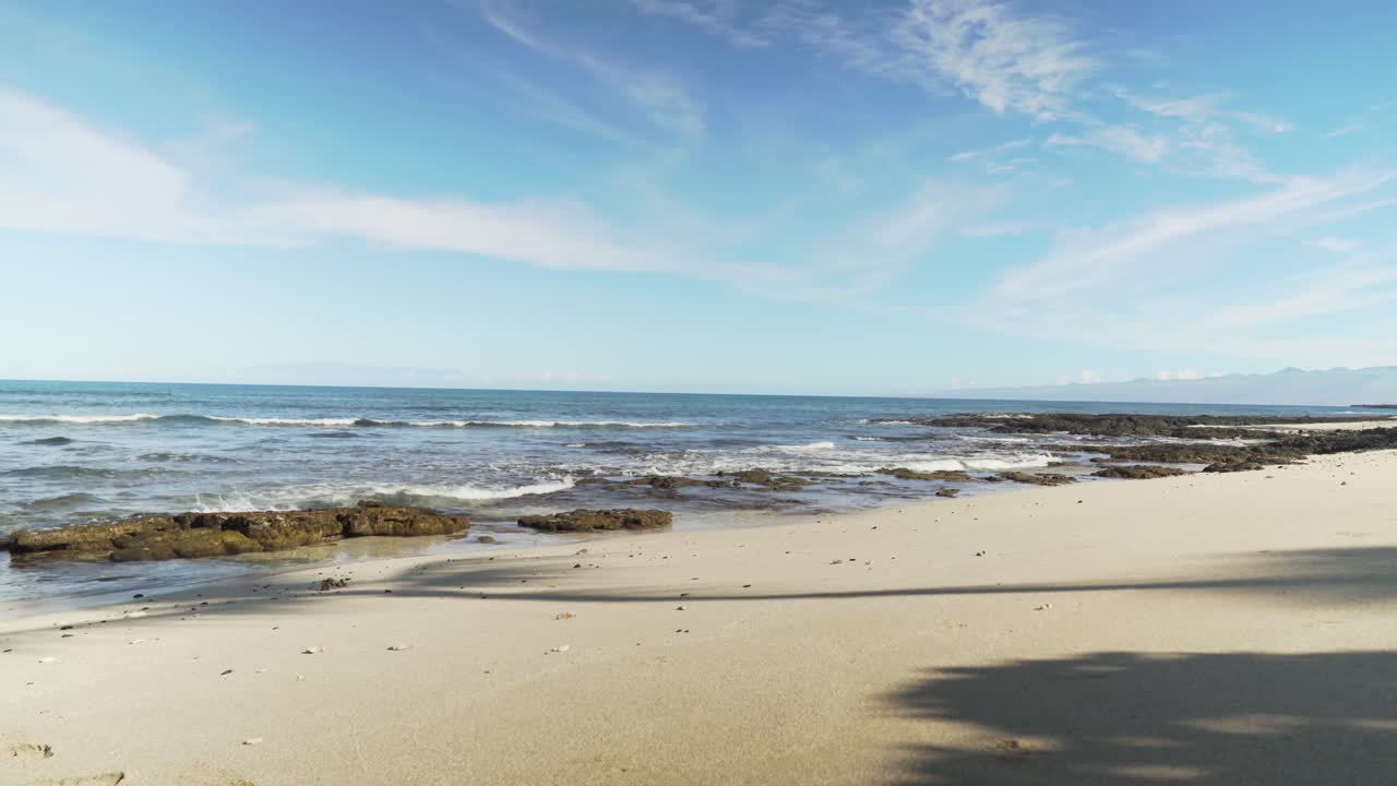 playa de arena amarilla con olas cubiertas de blanco que salpican formaciones rocosas de lava negra
