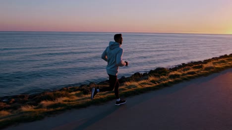 dedicated runner moving along coastal road during golden sunrise, experiencing scenic landscape with invigorating ocean views and fresh morning atmosphere