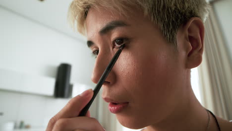 persona asiática que usa maquillaje en casa