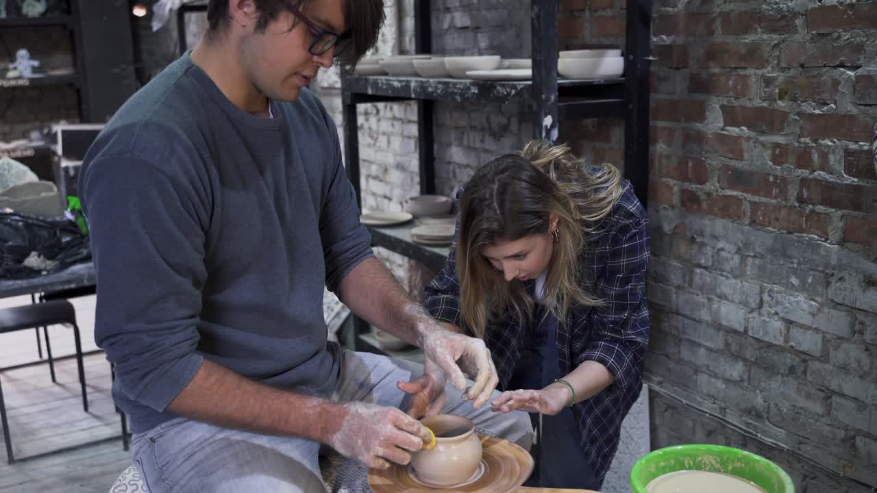 dos personas haciendo cerámica en una rueda de cerámica