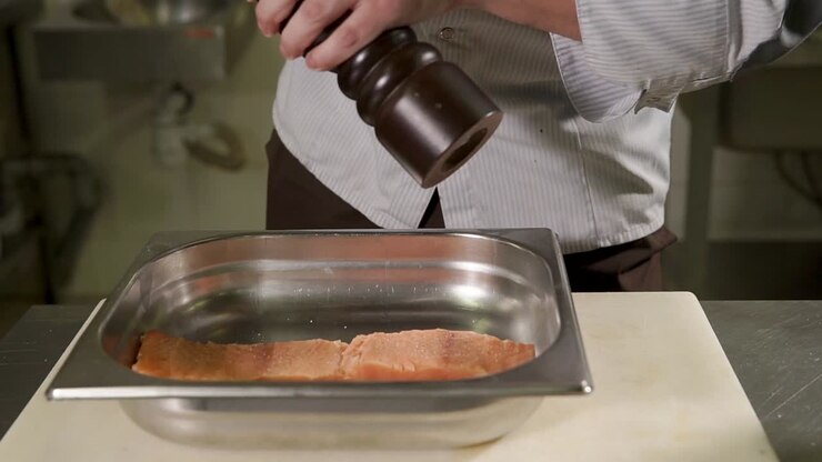 Chef che condisce il salmone