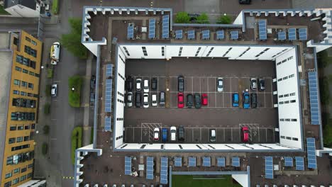 dolly right aerial view above energy efficient high rise solar panel rooftop with private carpark