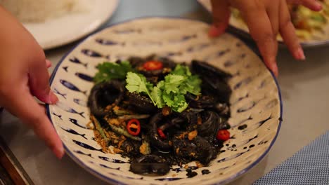 hands arranging a seafood dish with herbs