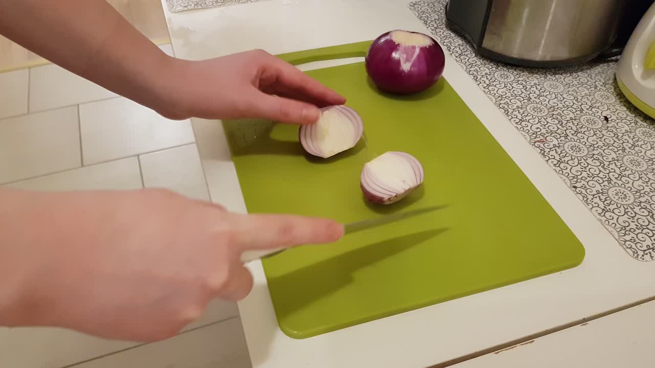 Caucasian woman cooking and cutting up purple onion