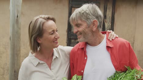 Sonriente-Pareja-Caucásica-Senior-Besándose-Y-Sosteniendo-Una-Canasta-De-Verduras