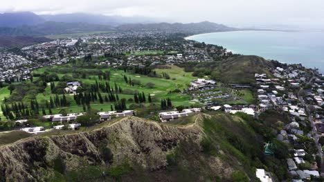 Disparo-De-Un-Dron-Viajando-Por-Una-Montaña-Hawaiana-Hacia-El-Paseo-Marítimo