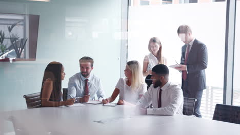 grupo que colabora en una tarea en el día de evaluación de la contratación de graduados mientras es observado por el equipo de contratación