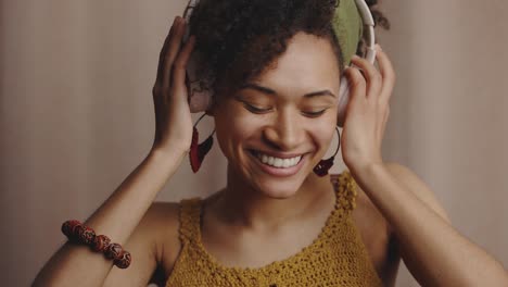 close up portrait of young authentic beautiful stylish black woman listening to music via headphones and dancing