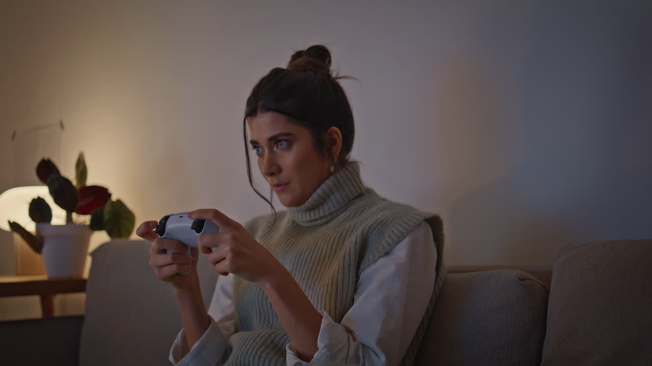 серьезная девушка игровой контроллер в ночное время дома крупный план. игрок наслаждается видеоигрой